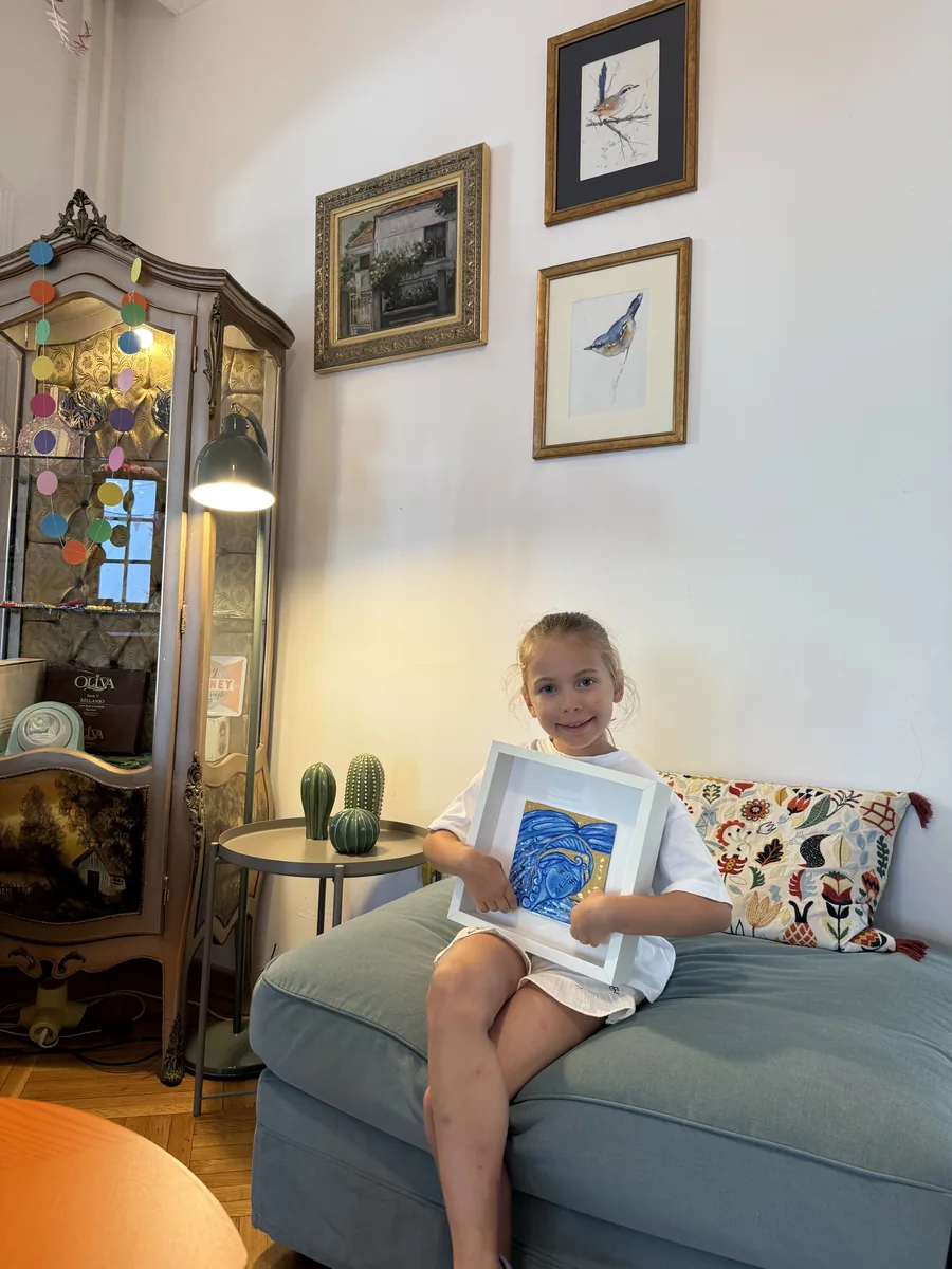 Devojčica drži svoju uramljenu sliku posle časa u ateljeu Artico